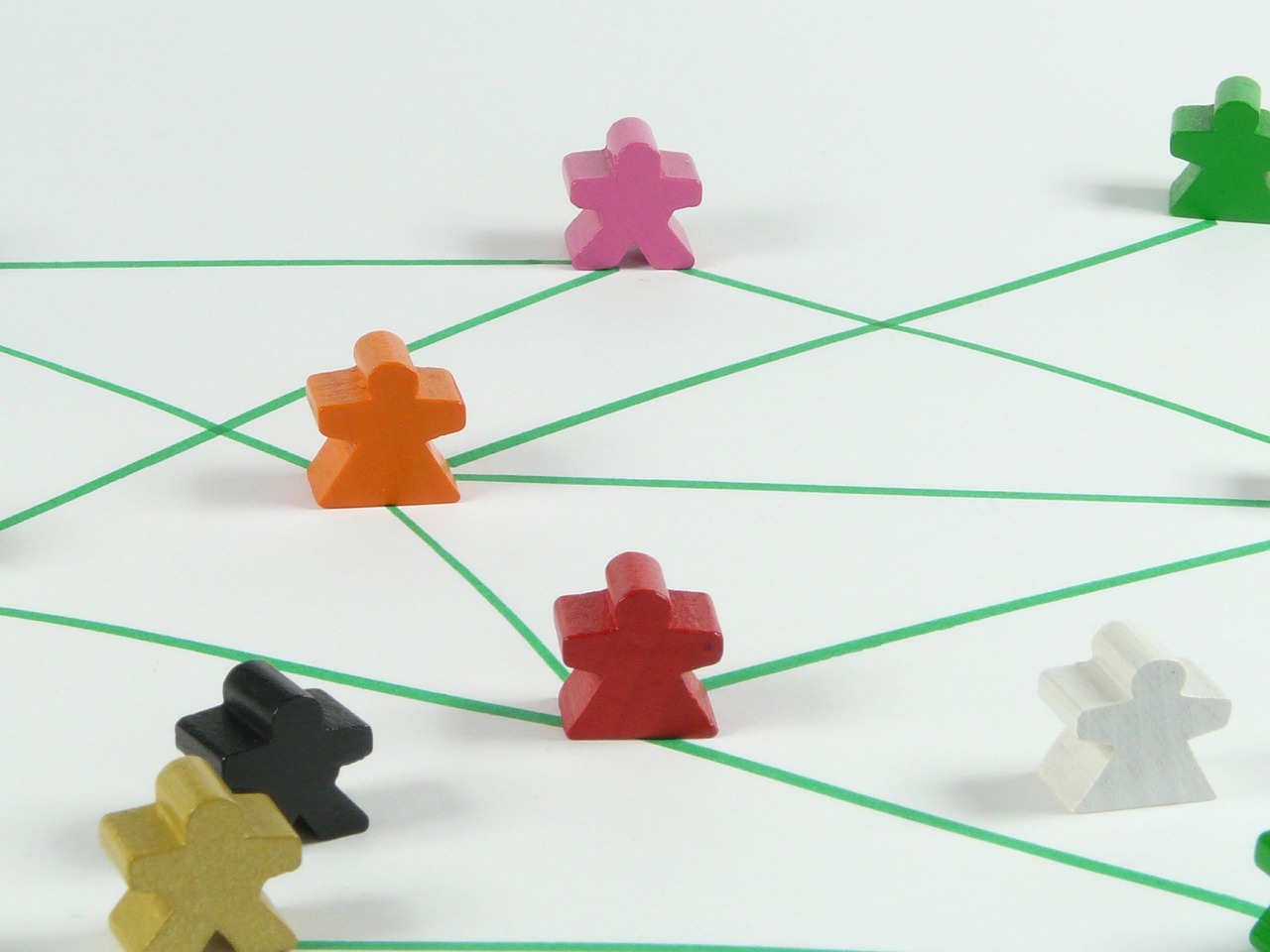 Several small, coloured figurines stand on a white floor, collected by green lines